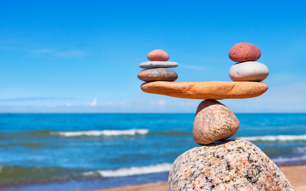 Rocks balanced in a stack with the ocean waves blurred in the background, creating a peaceful and serene coastal scene.